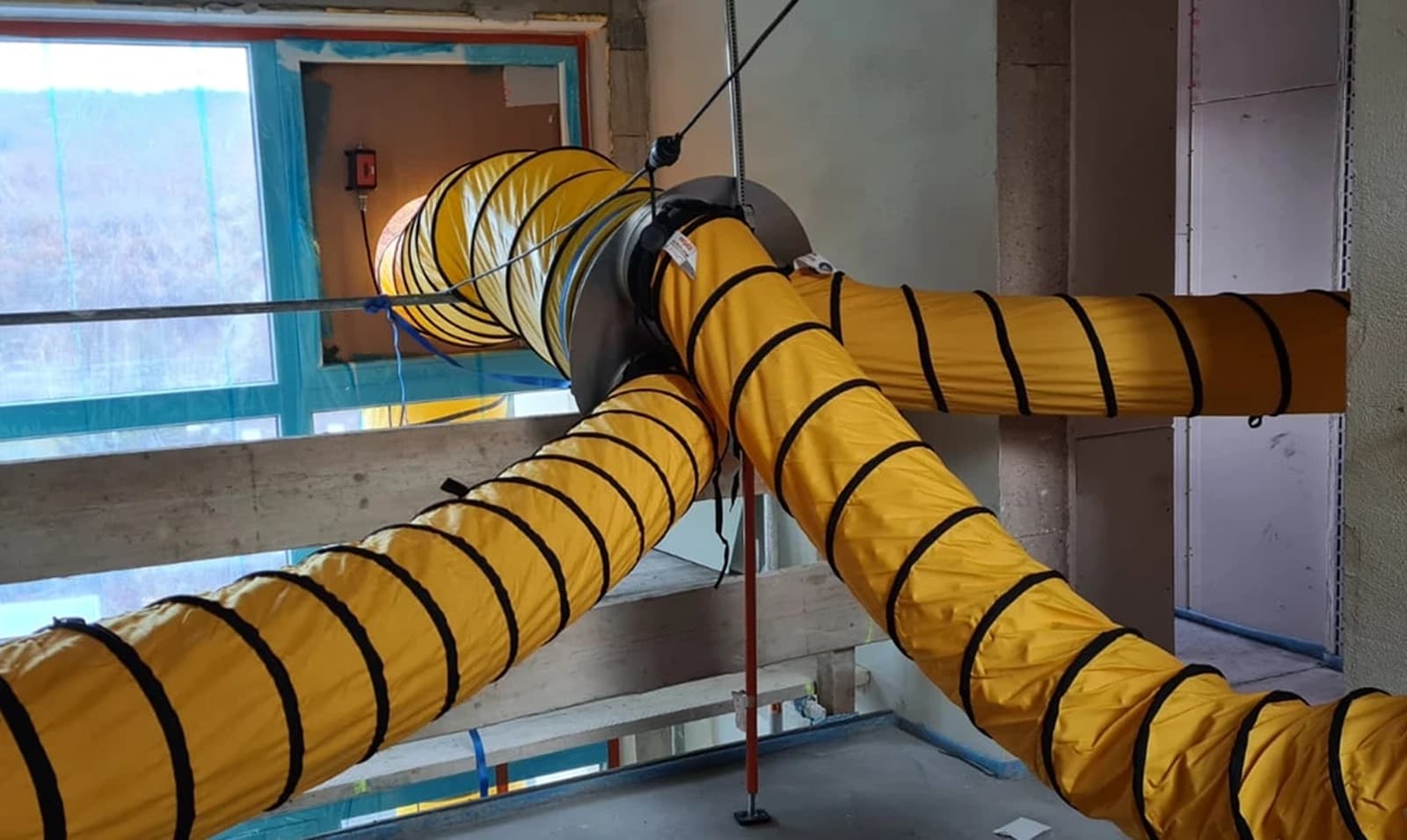Gelbe Warmluftschläuche einer mobilen Baubeheizung im Rohbau